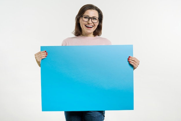 Sonriente mujer de mediana edad con cartel de hoja azul o cartel