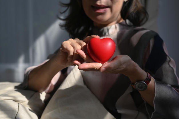 Sonriente mujer de mediana edad con forma de corazón Seguro de cuidado de ancianos salud del corazón y calidad de vida para el concepto de ancianos