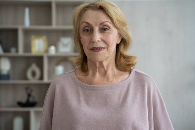 Sonriente mujer de mediana edad grayhaired madura mirando a la cámara feliz anciana posando en casa