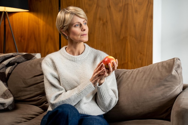 Sonriente mujer de mediana edad sosteniendo una manzana verde en sus manos concepto de alimentación saludable