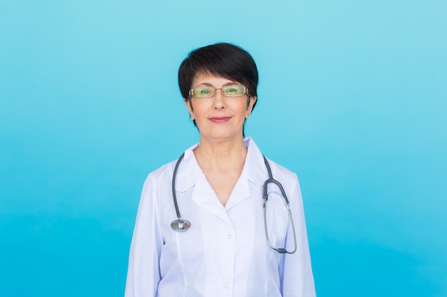 Sonriente mujer médico con estetoscopio. Sobre fondo azul con espacio de copia