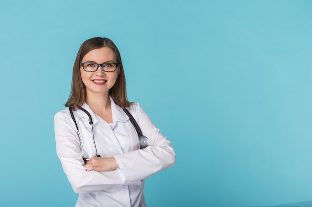 Sonriente mujer médico con estetoscopio sobre pared azul con espacio de copia