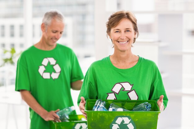 Sonriente mujer con mentalidad ecológica con caja de reciclaje