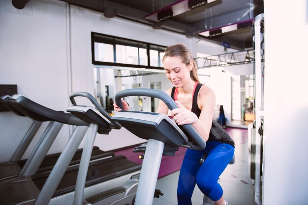 Sonriente mujer montando una bicicleta estática en el gimnasio