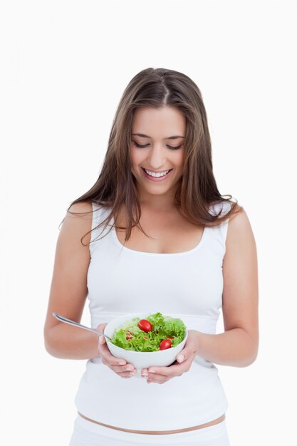 Sonriente mujer morena sosteniendo un plato de ensalada