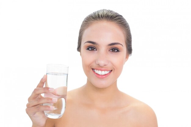 Sonriente mujer morena sosteniendo un vaso de agua