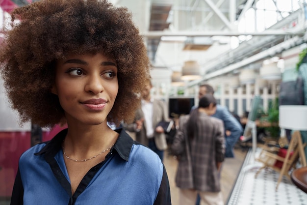 Sonriente mujer de negocios africana de pie en la oficina moderna en el fondo de los colegas