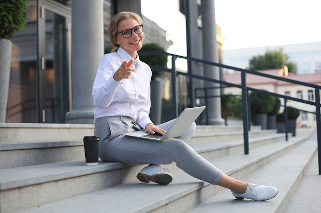 Sonriente mujer de negocios apuntando con su dedo.