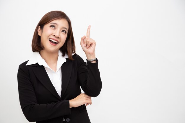 Sonriente mujer de negocios asiática apuntando hacia arriba aislado