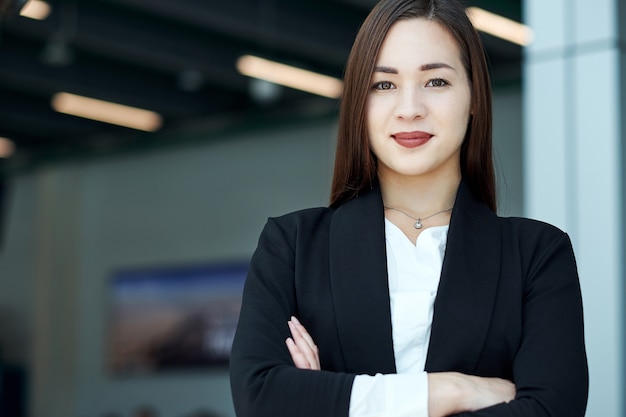 Sonriente mujer de negocios asiática en la oficina moderna o sala de reuniones. brazos cruzados.