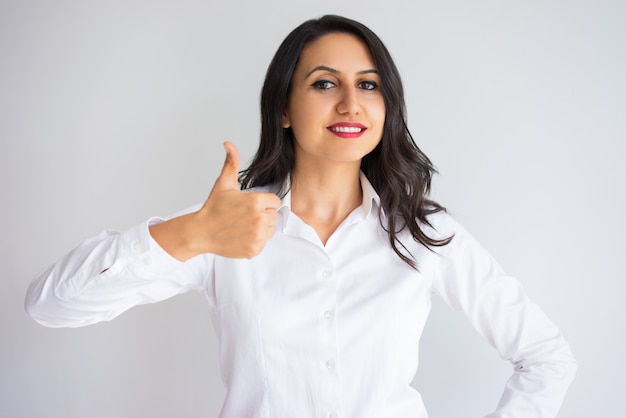 Sonriente mujer de negocios bastante mostrando el pulgar hacia arriba