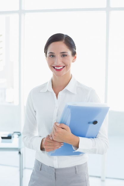 Sonriente mujer de negocios con carpeta en la oficina