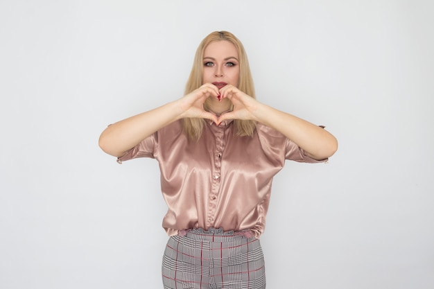 Sonriente mujer de negocios rubia en blusa rosa sobre fondo blanco.