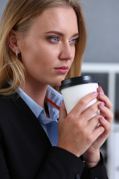 Sonriente mujer de negocios tomando café de un papel