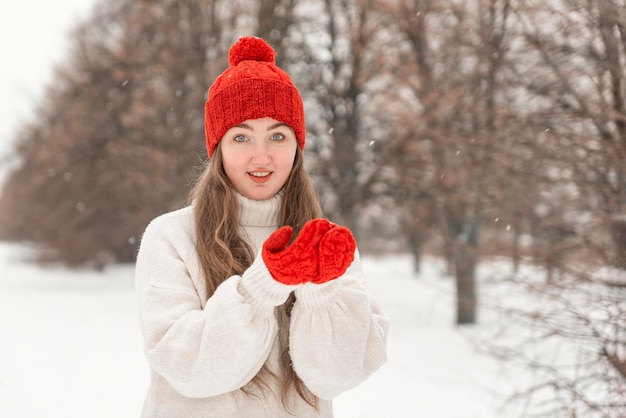 Sonriente mujer de ojos azules mira directamente a la cámara al aire libre Retrato de niña feliz caminando en el parque de invierno