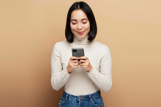 Sonriente mujer optimista de pie con el teléfono inteligente en las manos