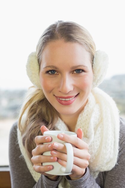 Sonriente mujer con orejera con café