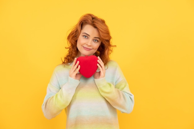 Sonriente mujer pelirroja con corazón rojo sobre donación de fondo amarillo