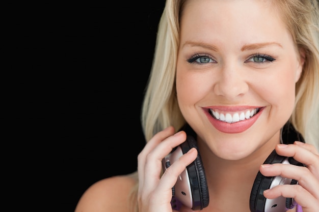 Sonriente mujer de pie mientras sujeta sus auriculares