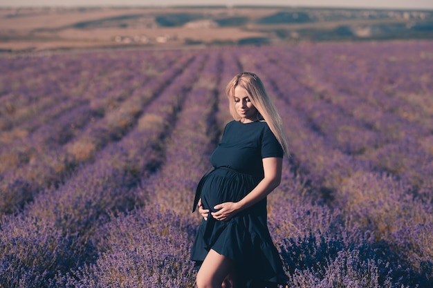 Sonriente mujer pregant en prado de flores de lavanda