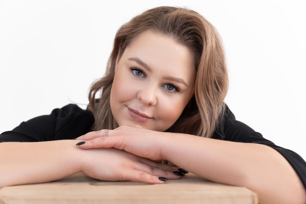 Sonriente mujer regordeta de mediana edad con el pelo largo y oscuro con cardigan negro sentado en la mesa poniendo c