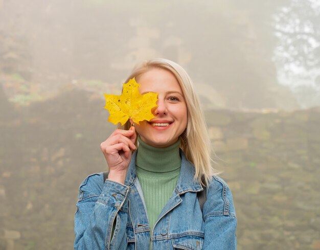 Sonriente mujer rubia con hoja de arce en un parque