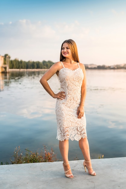 Sonriente mujer rubia posando en vestido de moda en la playa