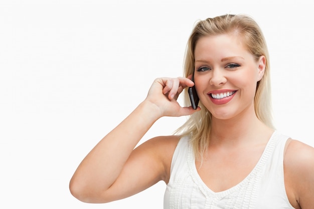 Sonriente mujer rubia sosteniendo un teléfono celular