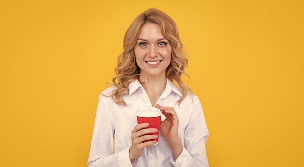 Sonriente mujer rubia con taza de café sobre fondo amarillo