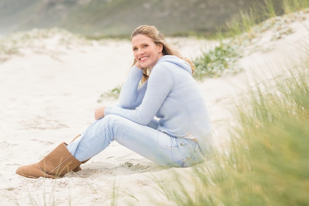 Sonriente mujer sentada en la arena