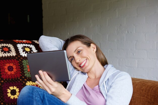 Sonriente mujer sentada en casa con tableta