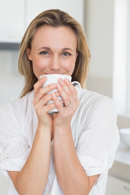 Sonriente mujer sentada y sosteniendo la taza