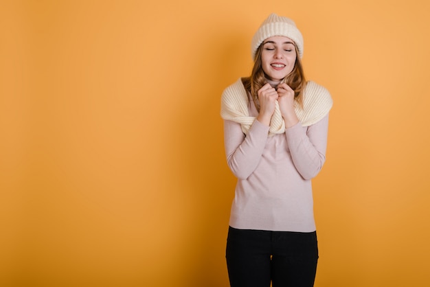 Sonriente mujer con sombrero y bufanda de invierno cerró los ojos