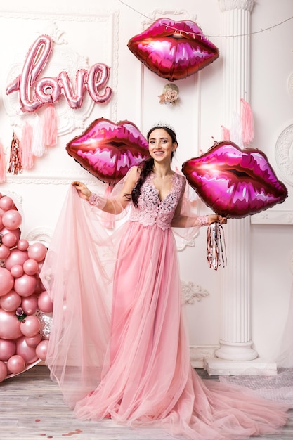 Sonriente mujer sorprendida feliz en vestido de tul con labios de globos rosa