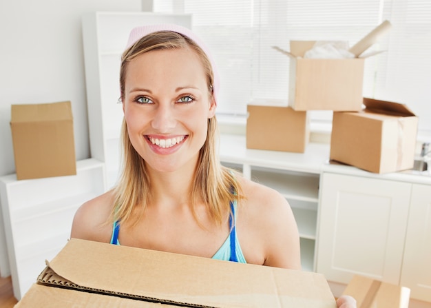 Sonriente mujer sosteniendo cajas después de mudarse