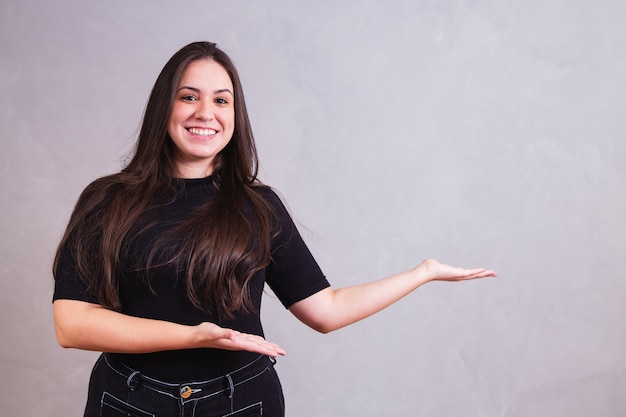 Sonriente mujer de talla grande apuntando hacia el lado con espacio para texto.