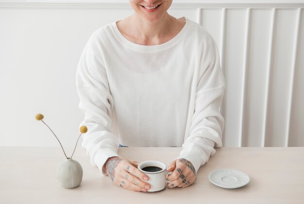 Sonriente mujer tatuada tomando un café