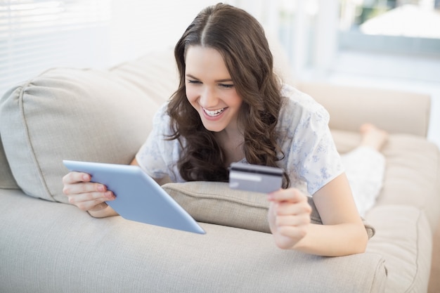 Sonriente mujer tendida en un sofá acogedor comprar en línea