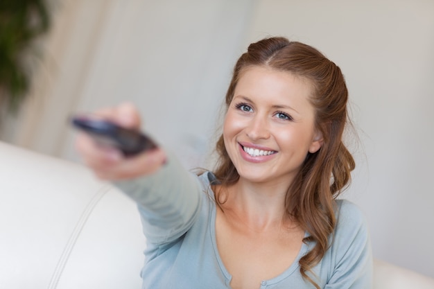 Sonriente mujer viendo la televisión en su sofá