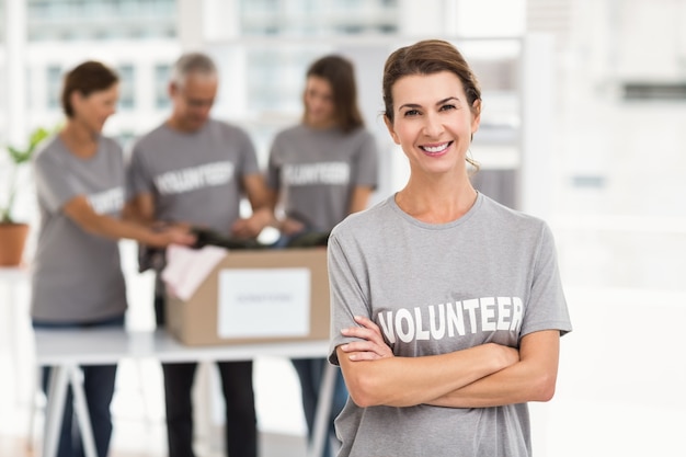 Sonriente mujer voluntaria con los brazos cruzados