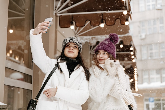 Sonriente a mujeres jóvenes vistiendo ropa de invierno abrigada charlando