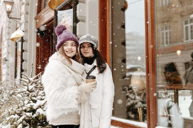 Sonriente a mujeres jóvenes vistiendo ropa de invierno abrigada charlando