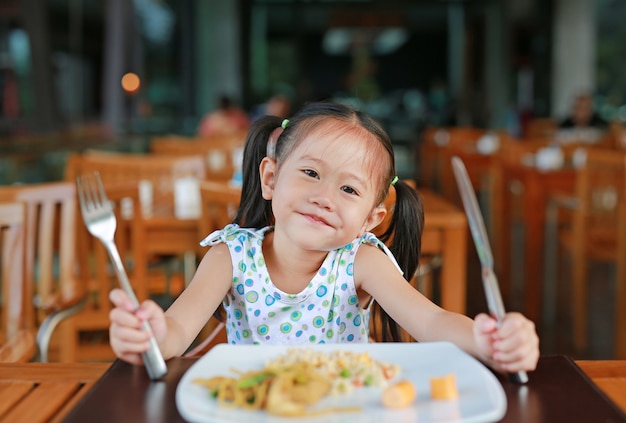 Sonriente niña asiática en el restaurante