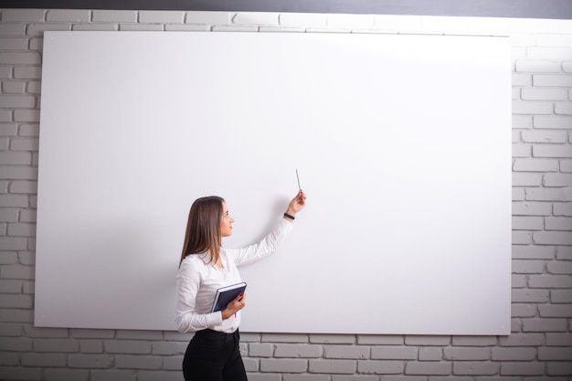 Foto sonriente niña estudiante o mujer maestra retrato en pared blanca