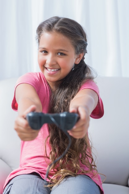 Foto sonriente niña jugando videojuegos en el sofá