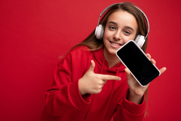 Sonriente niña morena hermosa positiva con sudadera con capucha roja