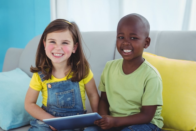 Sonriente niña y niño usando tableta