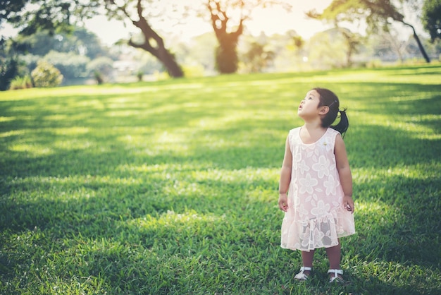 Sonriente niña de pie en el parque, tiempo feliz