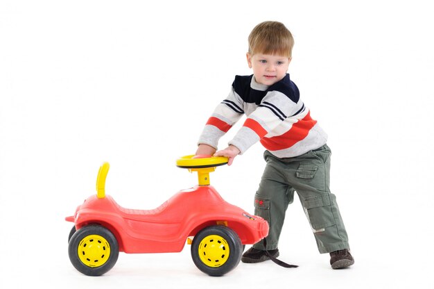 Sonriente niño juega con coche de juguete