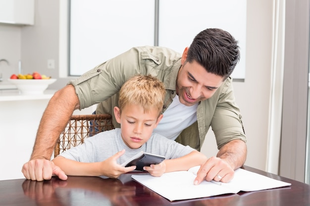 Sonriente padre ayudando a hijo con la tarea de matemáticas en la mesa